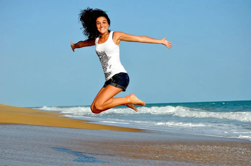 woman jumping on beach in happiness